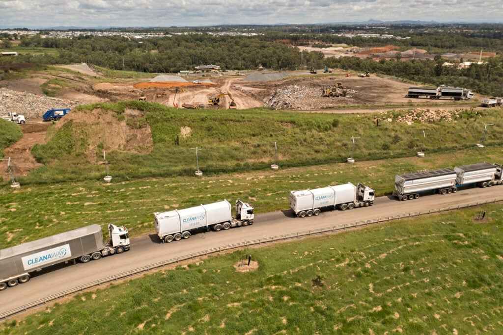Aerial view of a landfill site with waste trucks on the access road