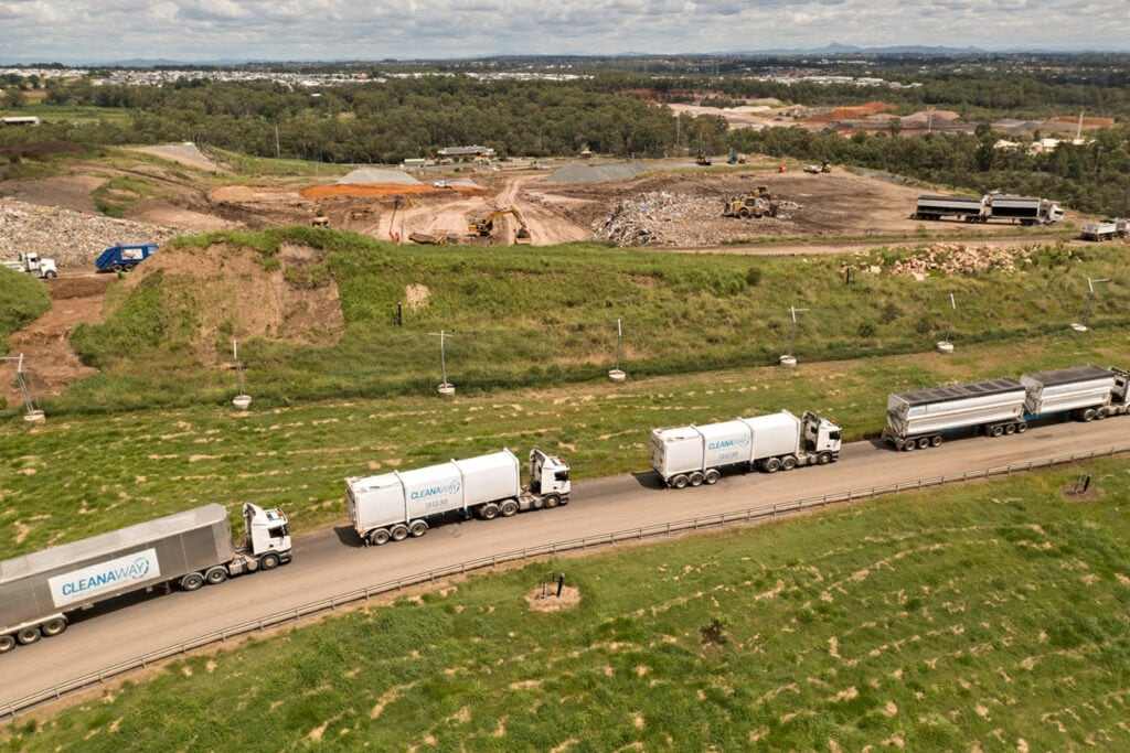 Aerial view of a landfill site with waste trucks on the access road